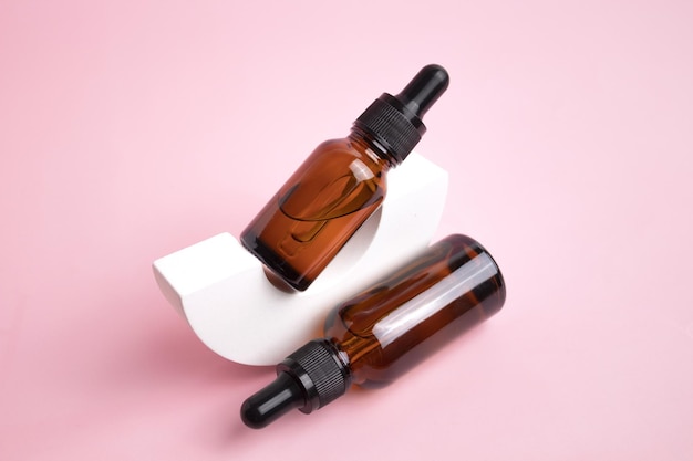 Piękno kolagenowe serum do twarzy w szklanej butelce z zakraplaczem w łuku na różowym tle Modna sesja opakowań kosmetyków Olejek eteryczny z naturalnymi składnikami