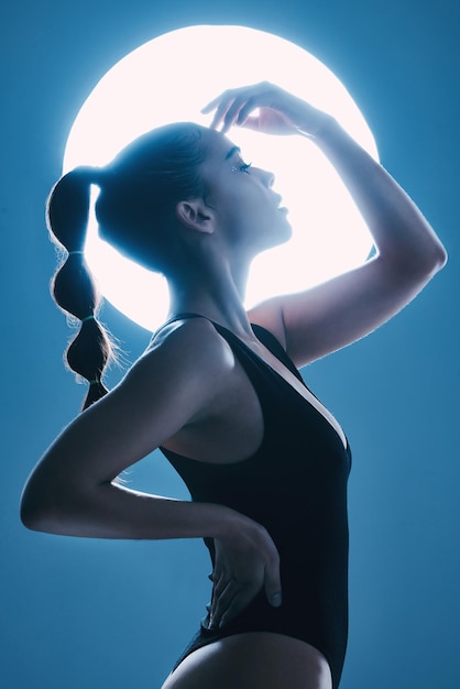 Piękno księżyca i profil kobiety w studio ze zmysłową miękką i atrakcyjną pozą Kosmetyczna magiczna i szczupła modelka z blaskiem pozującym przy świetle, odizolowana niebieskim tłem