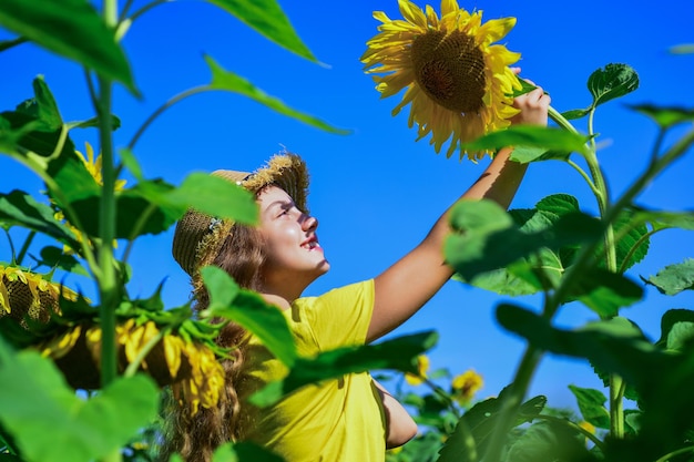 Piękno letniej natury mała dziewczynka w polu słoneczników żółty kwiat słonecznika szczęśliwe dzieciństwo piękna dziewczyna nosi słomkowy letni kapelusz w polu ładne dziecko z kwiatem