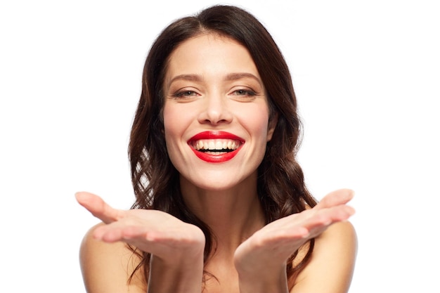 piękno makijaż i ludzie koncepcja szczęśliwa uśmiechnięta młoda kobieta z czerwoną szminką trzymając coś wyimaginowanego na dłoniach na białym tle