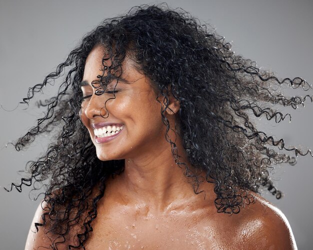 Zdjęcie piękno mokre i kobieta z zabiegiem do pielęgnacji włosów i pielęgnacji skóry dla odnowy biologicznej w studio zdrowie naturalny i szczęśliwy model z uśmiechem z brazylii poruszający włosami, odizolowany szarym tłem