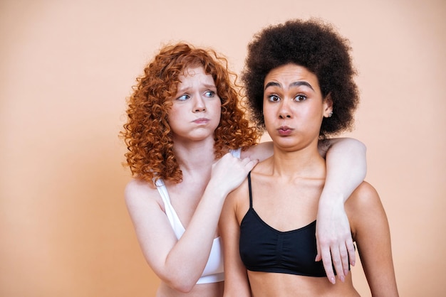 Piękno obrazu dwóch młodych kobiet o różnej skórze i ciele pozowanie w studio dla pozytywnej sesji zdjęciowej ciała. Mieszane modelki w bieliźnie na kolorowym tle
