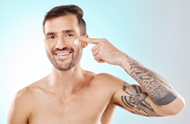 Piękno pielęgnacji skóry i portret mężczyzny z kremem wyizolowanym na niebieskim tle w studio Glow dermatologia i model stosujący balsam lub krem przeciwsłoneczny do pielęgnacji kosmetycznej i leczenia na tle