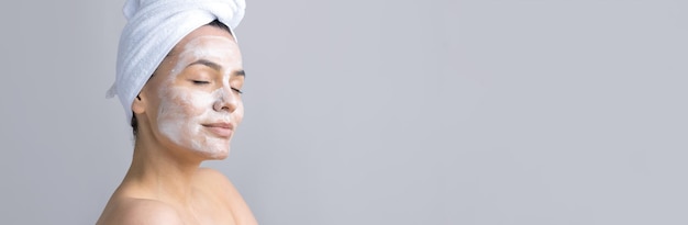 Piękno portret kobiety w białym ręczniku na głowie nakłada krem na twarz Pielęgnacja skóry oczyszczająca eko organiczny kosmetyczny spa relaks koncepcja