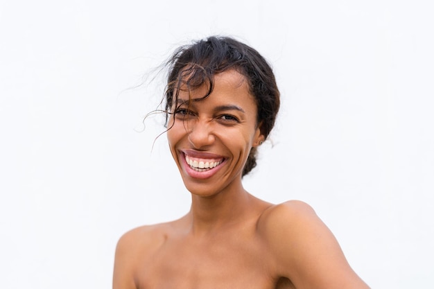 Piękno portret młodej Afroamerykanki topless z odkrytymi ramionami na białym tle z doskonałą skórą i naturalnym makijażem pozytywnym śmiechem