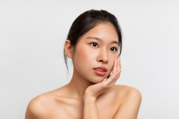 Piękno portret młodej azjatyckiej kobiety dotykającej jej czystej twarzy