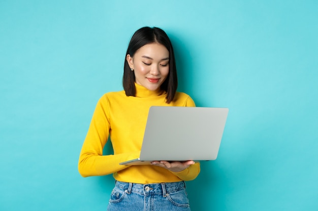 Piękny azjatycki studentka pracuje na laptopie
