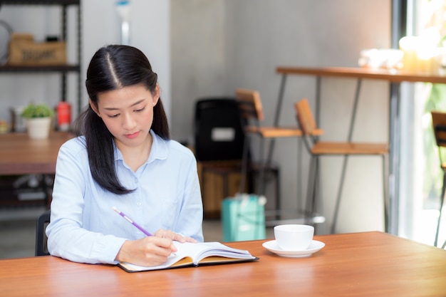 Piękny biznesowy azjatykci kobiety writing na notatniku na stole.
