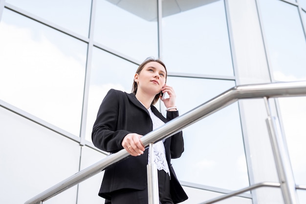 Piękny bizneswoman opowiada na telefonie komórkowym podczas gdy chodzić plenerowy