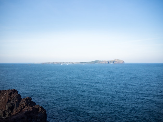 Piękny błękitny morze z czarną piasek plażą i niebem Jeju wyspa w koreańczyku