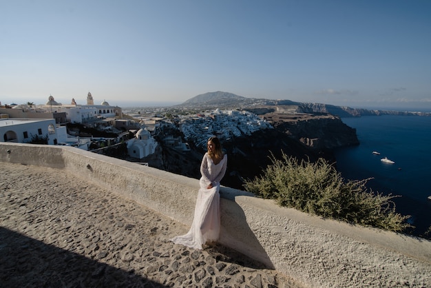 Piękny blond włosy młodej kobiety panna młoda niebieska w białej ślubnej długiej seksownej sukni na Santorini w Grecji