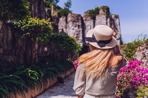 Piękny blondynki kobiety widok z powrotem chodzi i podziwia tropikalne krajobrazy przy rajskiej wyspy hotelem w Sanya, Chiny.