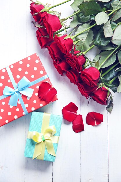 Piękny bukiet czerwonych róż i obecne pudełka na drewnianym tle