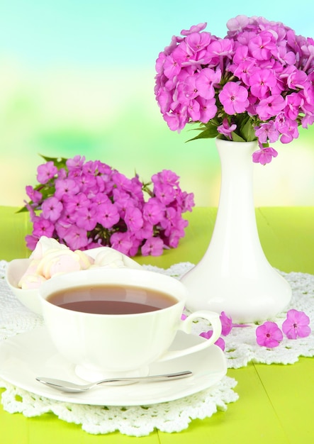 Piękny bukiet floks z filiżanką herbaty na stole na jasnym tle
