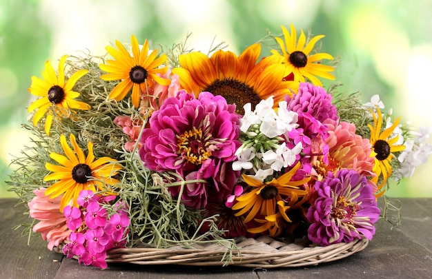 Piękny bukiet jasnych kwiatów na drewnianym stole na tle przyrody