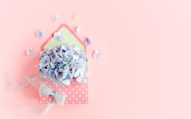 Piękny bukiet niebieskiej hortensji w kwiecistej kopercie na różowym tle płaski widok z góry