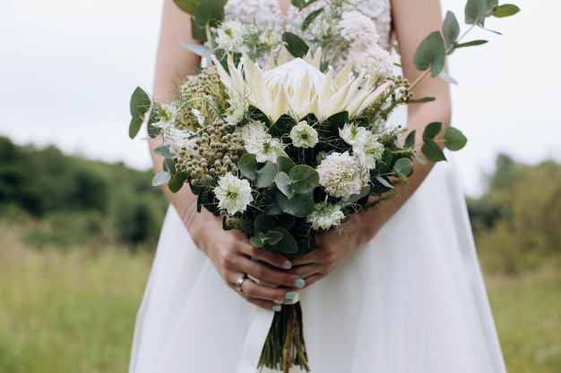 Piękny bukiet ślubny z białej protei w rękach Panny Młodej