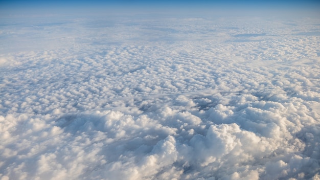 Piękny cloudscape z jasnym błękitnym niebem. Panorama nad białymi chmurami widziana przez okno samolotu. Widok z okna samolotu