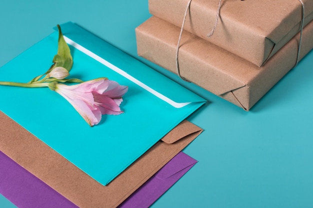 Zdjęcie piękny delikatny bukiet różowej alstremerii leżący na kopercie na niebieskim tle prezenty zapakowane w papier kraft obok kwiatów