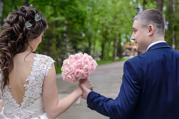 Piękny Delikatny Bukiet ślubny Z Różowych Róż W Rękach Młodej Pary Spacerującej Latem Po Parku