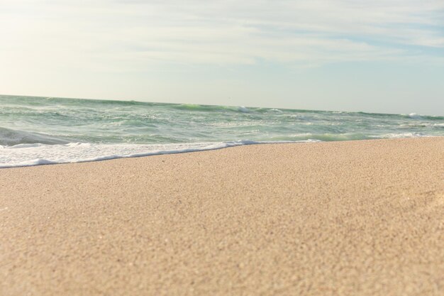 Piękny horyzont nad morzem z falami rozpryskującymi się na brzegu na słonecznej plaży na tle nieba