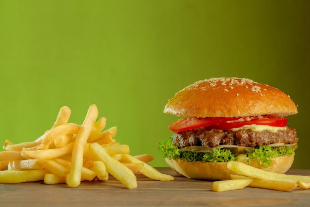 Piękny i smaczny burger i frytki na zielonym czystym tle