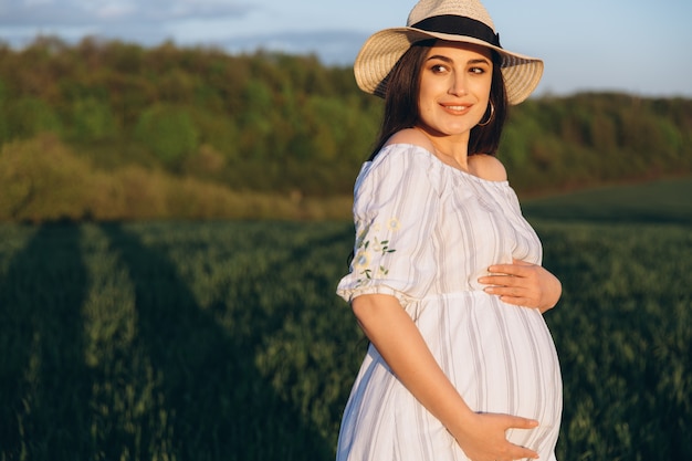 Piękny kobieta w ciąży w lato natury łące w zmierzchu