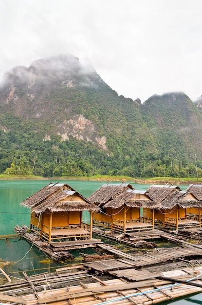 Zdjęcie piękny krajobraz przyrody zielonej góry i jeziora bambusa chata pływać w rząd stylu vintage country style w spokojny poranek, podróż do azji w parku narodowym khao sok, surat thani, tajlandia
