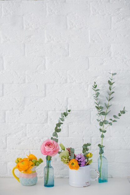 Piękny kwiat w różnych wazonach na tle białej ceglanej ściany Wiosenne kwiaty