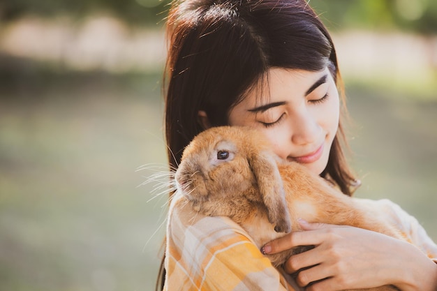 Piękny ładny Portret Młodej Azjatyckiej Kobiety Osoby Z Uroczym Królikiem W Koncepcji Opieki Nad Zwierzętami I Zwierzętami Szczęśliwa Kobieta Trzyma Królika W Przyrodzie Na Zewnątrz Pola Z Przyjaźnią Wielkanocną Koncepcją