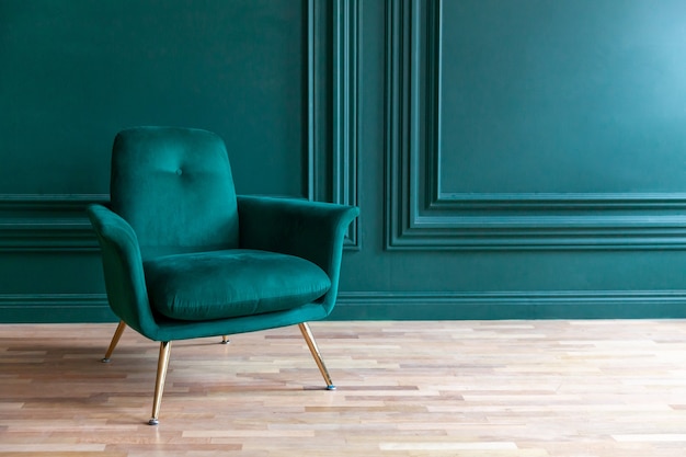 Piękny luksusowy klasyczny niebieski zielony czysty pokój w stylu klasycznym z zielonym miękkim fotelem. Vintage antyczne niebiesko-zielone krzesło stojące obok szmaragdowej ściany. Minimalistyczny projekt domu.
