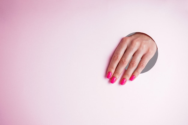 Piękny manicure z miejscem na tekst. Piękna kobieta ręka na różowym tle.
