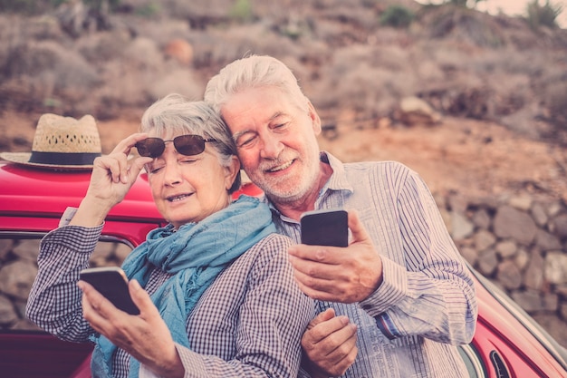 Piękny Mężczyzna I Kobieta Para Starszy Dojrzały Używać Smartfona Na świeżym Powietrzu W Czasie Wolnym Sprawdzając Internet W Poszukiwaniu Wiadomości E-mail I Znajomych Do Kontaktu. Wakacje I Styl życia. Ludzie Uśmiechający Się Razem