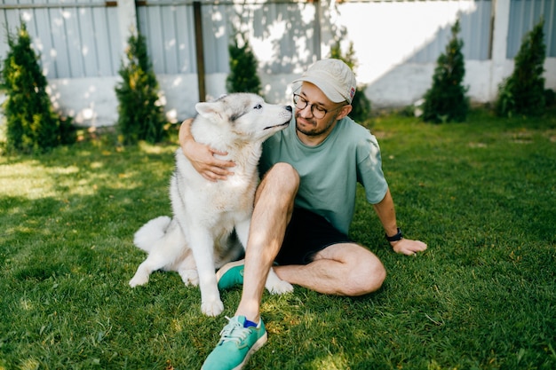 Piękny mężczyzna pozuje z psem na trawie