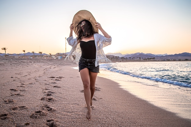 Piękny model boho w białej pelerynie na plaży w słońcu.