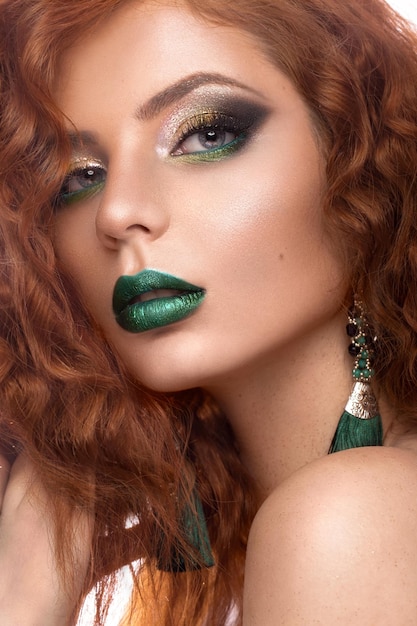 Piękny model redhair zwija jasną biżuterię do makijażu i zielone usta Piękna twarz