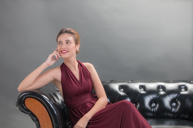 Zdjęcie piękny mody kobiety modela obsiadanie i uśmiechnięty pozować na kanapie