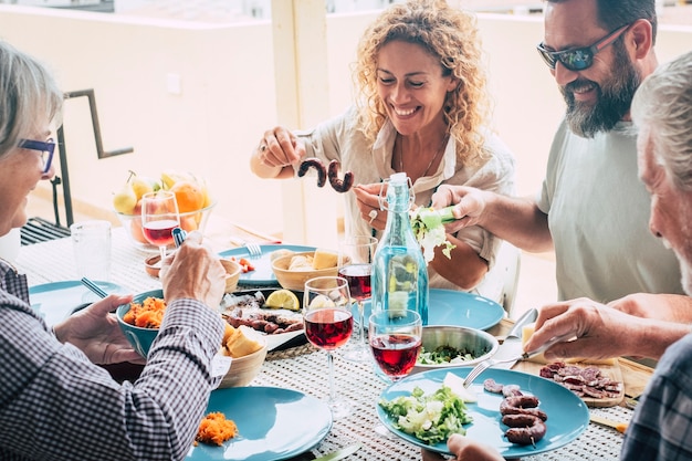 Piękny moment życia rodzinnego w domu, jedzenie i picie jedzenia lub napojów w domu na stole - człowiek z okularami przeciwsłonecznymi tking warzyw - stół pełen jedzenia i sałatki na świeżym powietrzu