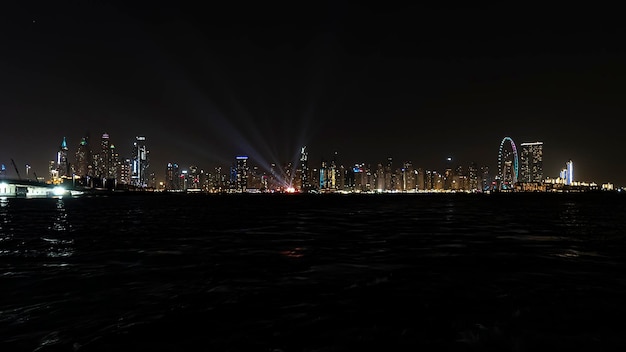 Piękny nocny widok drapaczy chmur w Dubaju z morskiej panoramy Dubai Marina po zachodzie słońca z morzem na pierwszym planie