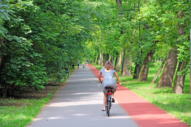 Piękny park miejski z bieżnią i kobietą jeżdżącą na rowerze Młoda kobieta jeżdżąca