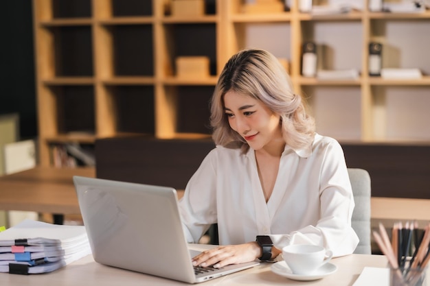 Piękny portret azjatycki bizneswoman menedżer uśmiechający się w biurze z laptopem w nowoczesnym biurze siedzącym online marketingowa komunikacja finansowaxA