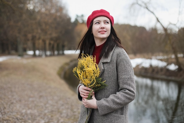 Piękny portret młodej kobiety z kwiatami mimozy na zewnątrz