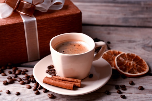 Piękny prezent, kubek z kawą i ziarnami kawy na drewnianym tle