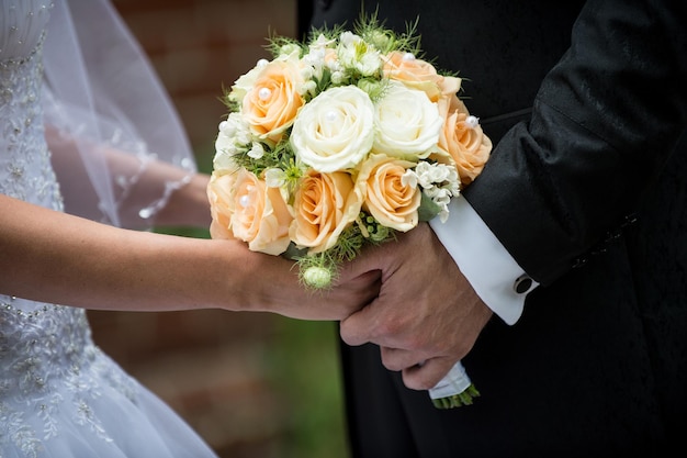 Piękny ślubny bukiet róż w rękach panny młodej i mężczyzny