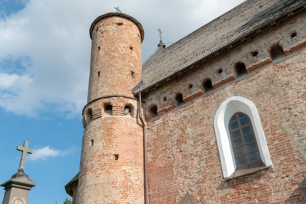 Piękny stary kościół forteczny wykonany z czerwonej cegły na tle błękitnego nieba Wysoka nie do zdobycia forteca z żelaznymi krzyżami na łukowych oknach kopuł i ikoną pośrodku ściany