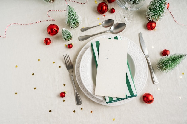 Piękny świąteczny stół z miejscem na menu lub zaproszenie na białych talerzach ze srebrnymi sztućcami