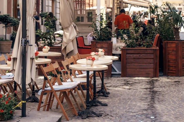 Piękny taras kawiarni z małymi zabytkowymi stołami i drewnianymi krzesłami i roślinami nowoczesna fasada restauracji w europejskim mieście street food court na starym mieście