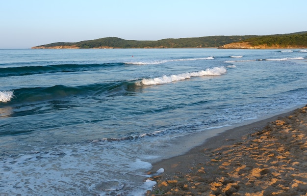 Zdjęcie piękny widok na wybrzeże morza z plaży z falami surfowania i odbiciem słońca na piasku.