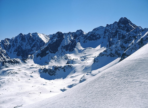Zdjęcie piękny widok pokrytych śniegiem gór na tle jasnego niebieskiego nieba