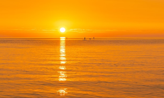 Piękny widok pomarańczowego zachodu słońca odbitego na jeziorze z surferami nad jeziorem Michigan